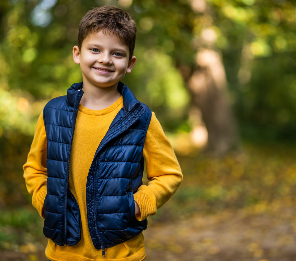 Young boy standing in nature smiling